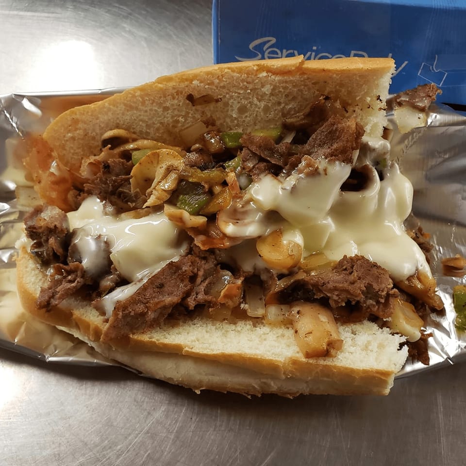 TNT Takeout's cheesesteak sandwich, filled with steak, melted cheese, mushrooms, and peppers, in foil.